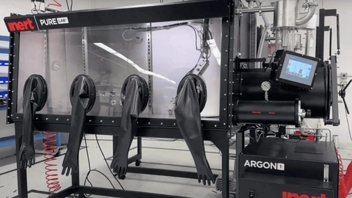 Industrial laboratory glove box unit with four black rubber gloves and an argon gas purifier on the right